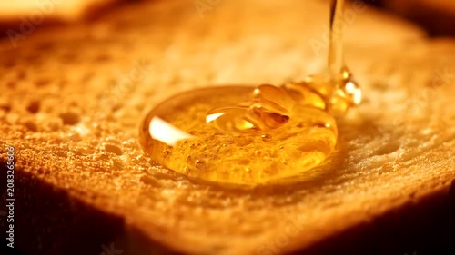 Golden Honey Drizzling onto Toasted Bread Slice for a Sweet Breakfast Treat.