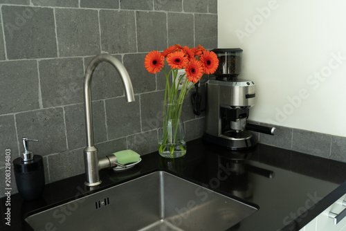 Cuadro en lienzo Orange gerbera daisies brighten a kitchen counter, placed next to a sink and a coffee grinder for a fresh morning atmosphere