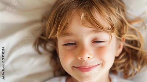 Cute little child lying in bed and smiling looking at camera close up video