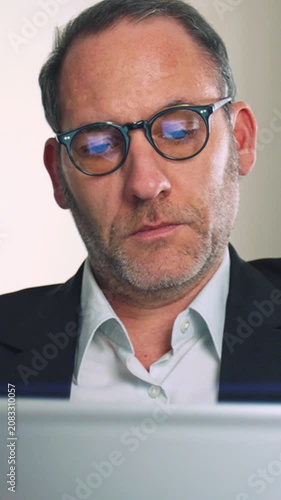 Businessman with glasses working on mobile device - vertical video