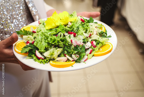 Slika na platnu Fresh mixed green salad carried by a guest during a catered event