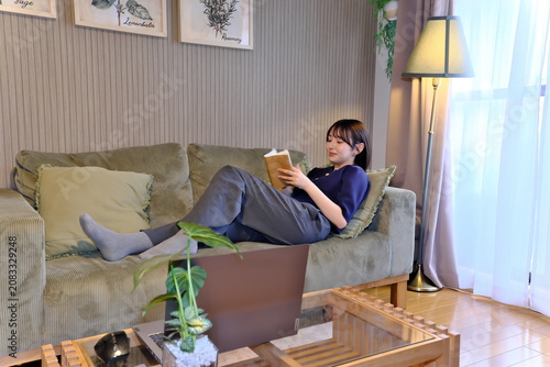 фотографія 癒しの「自分時間」。ソファで寝ころびながら読書に没頭する女性の穏やかなライフスタイルシーン