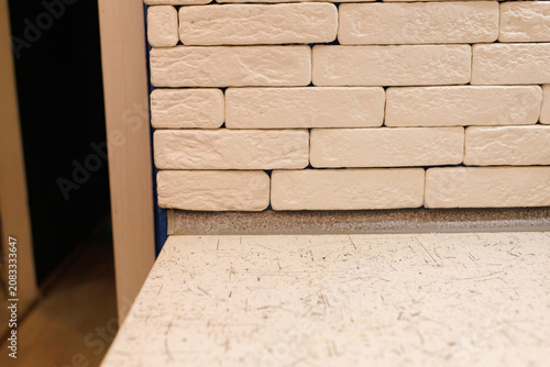 The scene shows a white brick wall next to a countertop in a kitchen setting