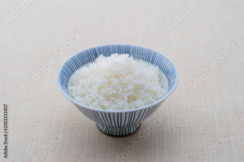 A bowl of steaming white Japanese rice served in a traditional blue patterned ceramic bowl