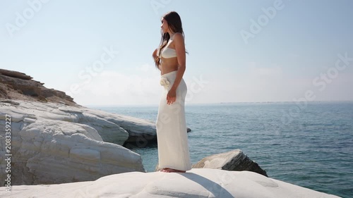 Stylish woman enjoying the sea breeze on white coastal rocks