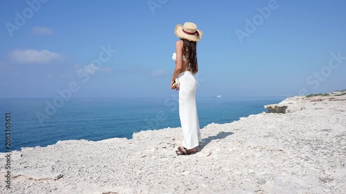 Beautiful young woman in a straw hat enjoying the summer sea view