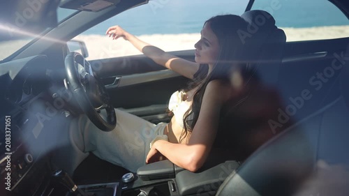 Young woman enjoying the sun while relaxing in a convertible car