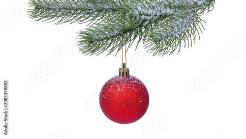 Red glitter Christmas ornament hanging from snow-covered pine branch