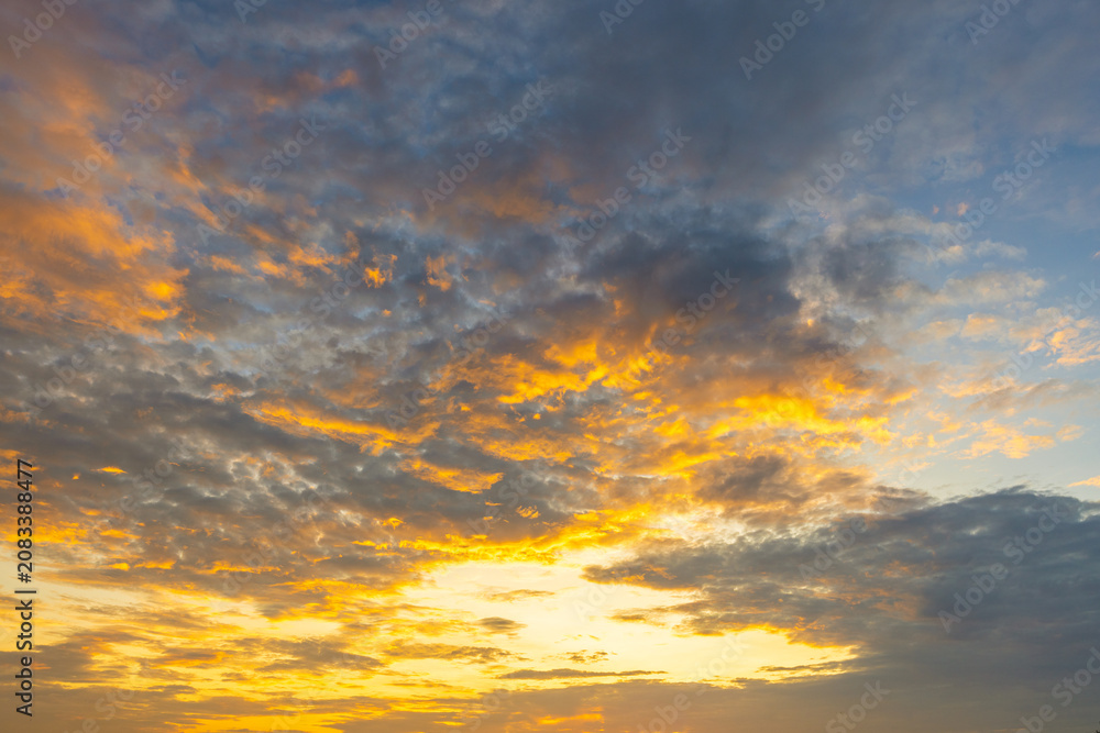 Fototapeta premium Golden Sunset Sky with Dramatic Clouds,A breathtaking view of a vibrant golden sunset sky filled with textured clouds, creating a peaceful and inspiring atmosphere.