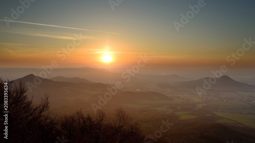 Photos Hazy Golden Sunset over Volcanic Peaks with a Long Jet Contrail Crossing the Sky