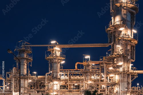 Oil Refinery Plant Illuminated with Glowing Lights and Distillation Column Pipe and Industrial Towers