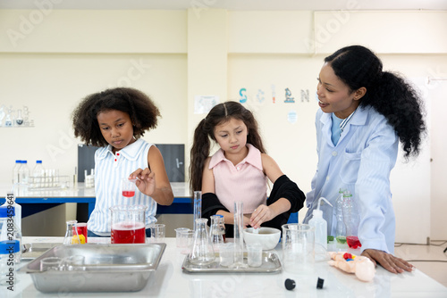 Very happy African female teachers and two young girls conducting a science experiment in a laboratory