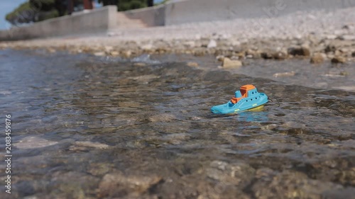 A small toy boat struggles against incoming waves before tumbling in the surf, creating a powerful visual metaphor for fragile childhood dreams challenged by life's obstacles. Slow-motion water