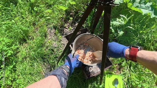 Man frying lard in camp pot