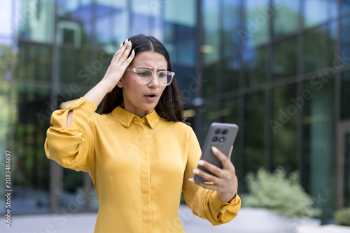 Εκτύπωση καμβά Young woman looking shocked and frustrated while reading disturbing news on her