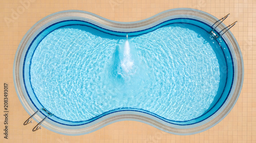 Swimming pool with blue water and a central fountain creates a refreshing summer environment.