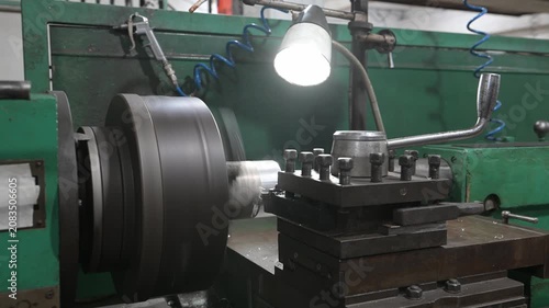 A lathe is located in the production workshop. The electric lathe removes a layer of rust from a coated metal workpiece, creating the shape of the finished product. Metal manufacturing.