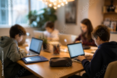 Group of children using laptops for school work in a modern bright dining room