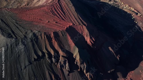 An aerial close-up drone shot focusing on the dramatic textures, eroded ridges, and sharp color contrast between black basalt ash and red iron oxide slopes of a volcanic crater in El Pinacate, Mexico.