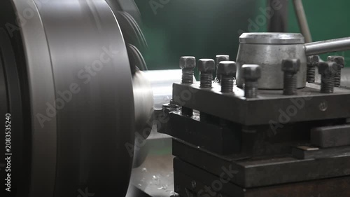An electric lathe removes a layer of rust from a coated metal workpiece, creating the shape of the finished product. Metal manufacturing.