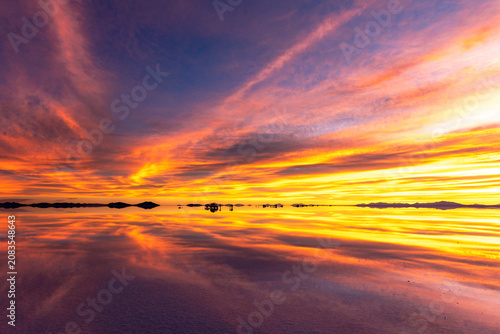 Sunset at the Salar de Uyuni, the world’s largest salt flat, under a sky ablaze with the colors of sunset, in the Andean region of Bolivia.