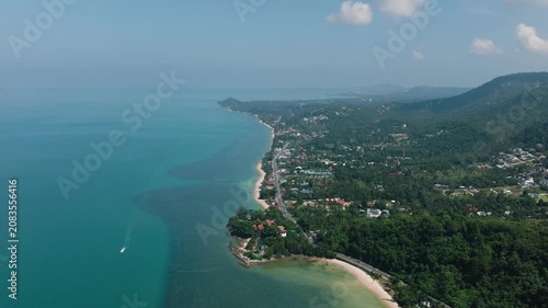 A long coastal stretch with turquoise waters, lush greenery, and a scenic horizon extending into the distance. Ko Samui, Thailand.