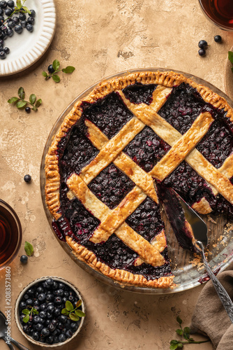 Blueberry pie with lattice crust sliced on brown textured table background close up, traditional homemade dessert concept top view