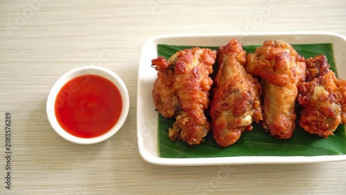 Fried chicken drumsticks with spicy red sauce on a white plate