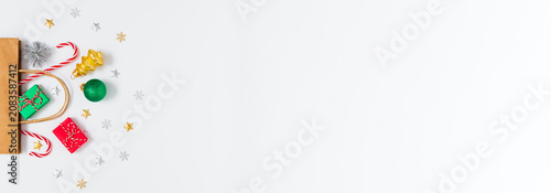 Gift bag with tiny presents, ornaments, candy canes on white background. Ideal for holiday banners, winter festive sales, marketing and Christmas promo layouts. Flat lay, copy space.