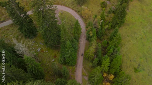 Aerial drone view of a man pushing a gravel bike uphill toward Soinsee lake. This moody autumn ascent is located near Bayrischzell in the Mangfallgebirge mountains, Bavarian Prealps, Germany