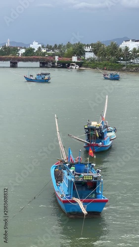 Blue wooden fishing boats moored in calm tropical harbor under overcast sky with diagonal composition