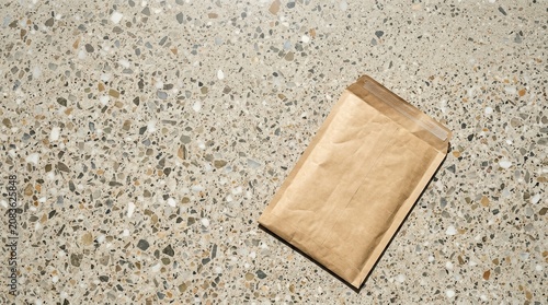 Paper shipping mailer mockup placed on a textured concrete surface, showcasing a clean and minimalistic design suitable for packaging and shipping purposes