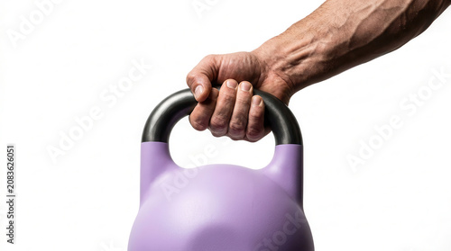 Hand lifting a pastel purple kettlebell with a black handle, showcasing muscular definition and grip strength against a white background