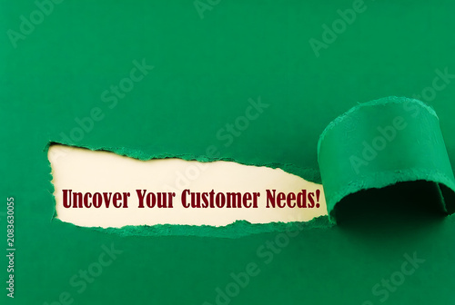 Uncover Your Customer Needs Message Revealed Through Torn Paper On emerald green Background For Marketing Research And Business Strategy Concept