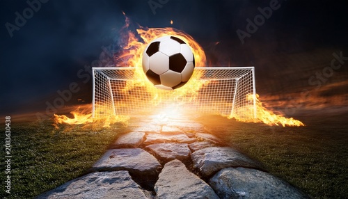 dramatic image of a flaming soccer ball flying into a goal net above a glowing stone path at night