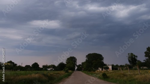 Country road under dark dramatic thunderstorm sky with approaching lightning storm