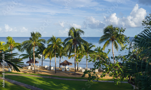 Fotografie Tropical beach hotel resort on sea with sun loungers and palm trees during a war