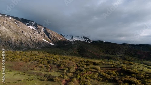 Distant snow-capped peaks stand against a cloudy sky