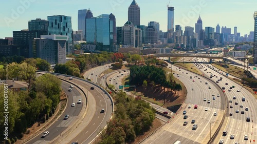 Rush hour highway traffic driving past Atlanta city landscape with tall skyscraper buildings. Fast urban rhythm, daily commute and metropolitan lifestyle.