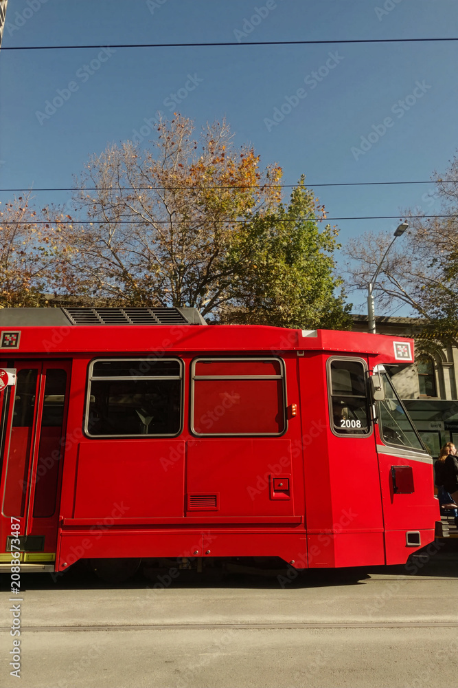 Obraz premium Side Profile of Red Light Rail Vehicle on City Street - Modern Urban Public Transportation and Transit Infrastructure