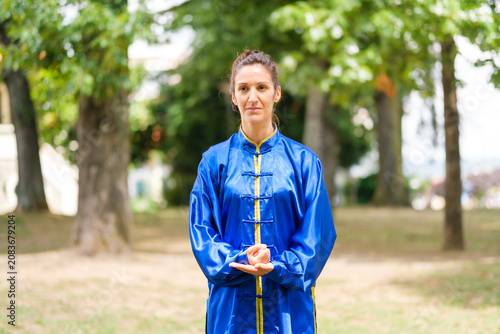 Bild auf Leinwand Woman practicing tai chi in blue uniform outdoors
