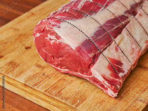 Huge carvery rib roast on the bone is on a wooden cutting board. Butcher craft and skill product. Top quality beef meat with high value and price tag due to premium cut and complicated production.