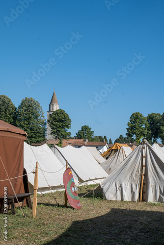 Photography Roman Reenactment Camp with Canvas Tents and Painted Shield Under Blue Sky