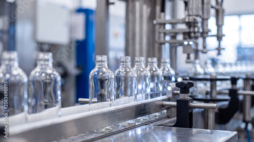 Billede på lærred Automated production line with glass bottles on conveyor belt