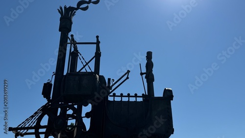 Photos Vintage Steam Engine Sculpture: A striking silhouette of a vintage steam engine sculpture against a clear blue sky, exuding a sense of industrial heritage and mechanical wonder