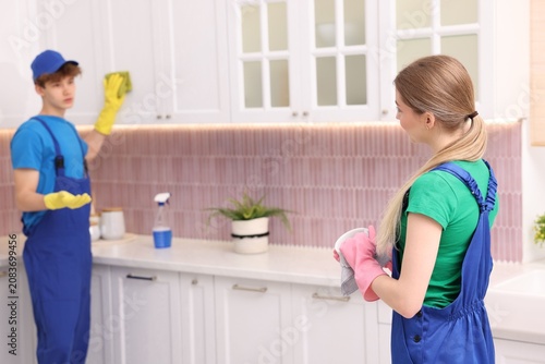 Fotografie Teenage workers wiping dishes and cleaning kitchen, selective focus