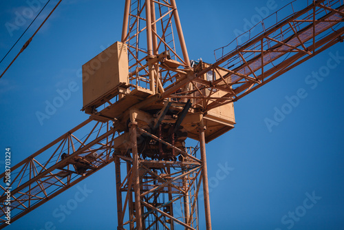 Картината върху платно Close-up of a yellow tower crane jib end against clear blue sky with large copy