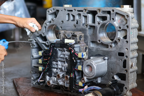 Canvastavla Mechanic Cleaning Transmission Valve Body with Air Duster.