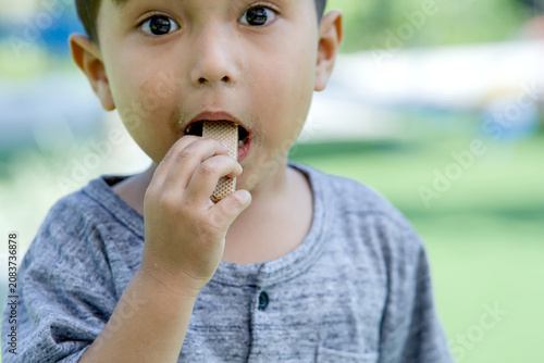 Canvastavla Wide-Eyed Boy Eating Snack with Curious Expression