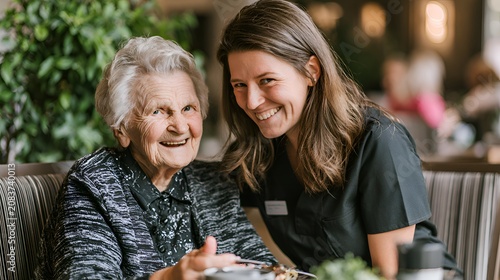 Joyful senior woman and young caregiver smiling side by side